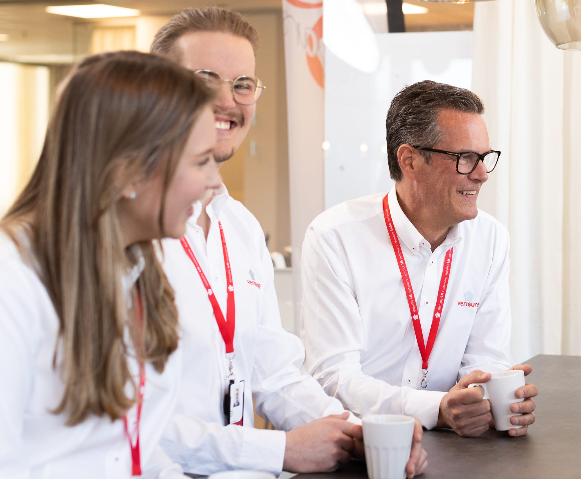 Employees in Verisure uniforms having a relaxed conversation over coffee.