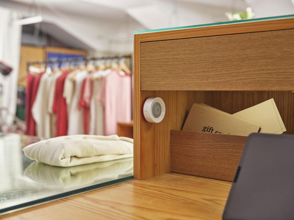 Verisure Smart Remote device mounted on a wooden counter in a retail environment.