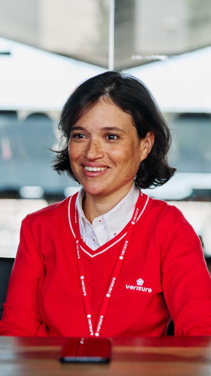 Female Verisure employee in red uniform speaking during meeting.
